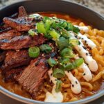 A bowl of Spicy Korean Ramen topped with grilled beef, creamy sauce, and green onions.