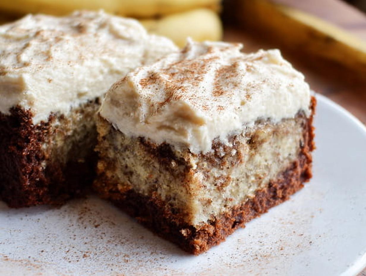 Close-up of two slices of Banana Bread Brownies Made Easy, topped with creamy frosting and a sprinkle of cinnamon.