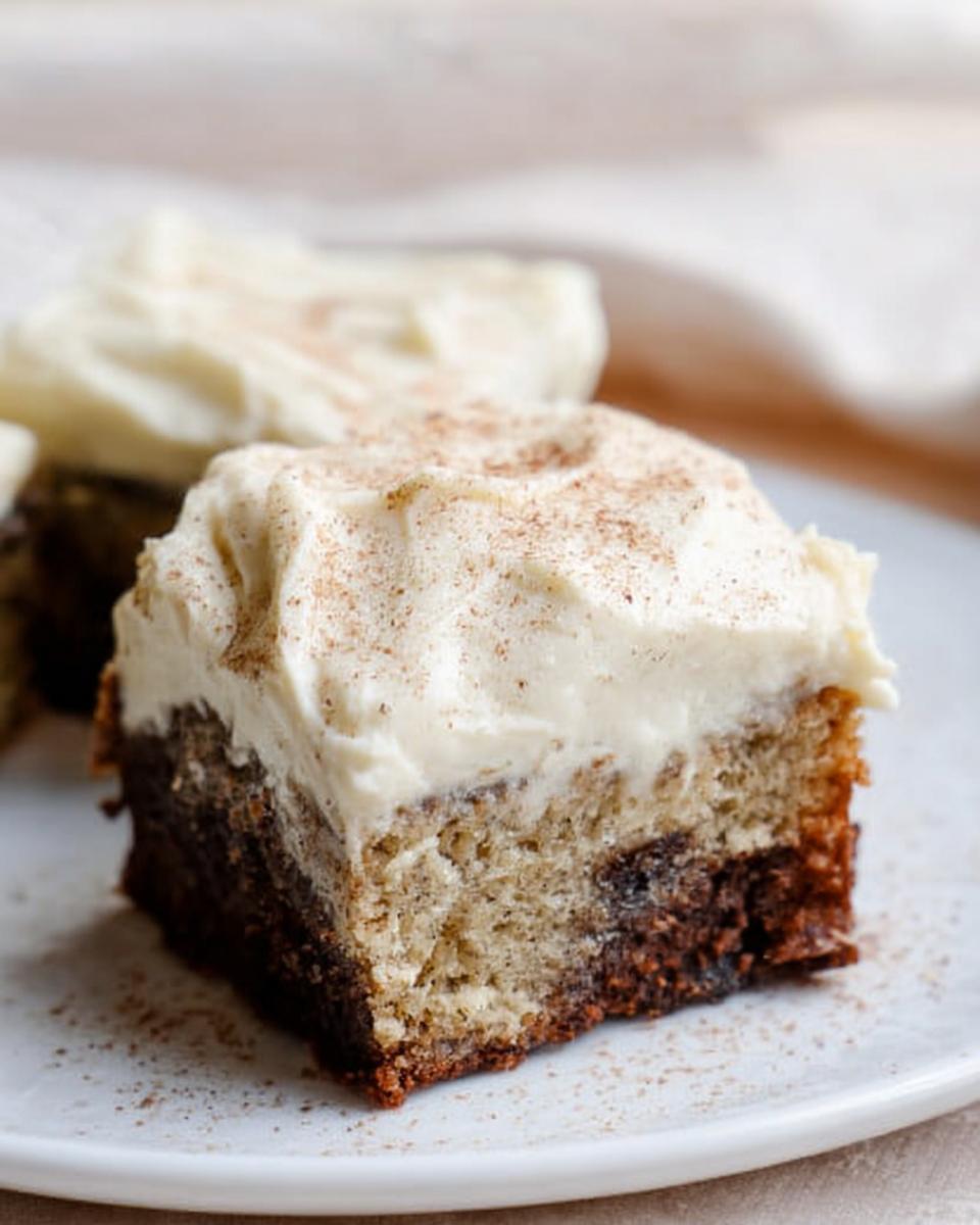 A close-up of a slice of Banana Bread Brownies Made Easy, topped with creamy frosting and a sprinkle of cinnamon.
