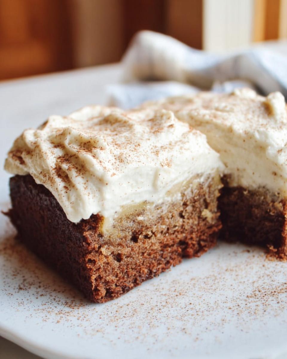 Close-up of two slices of Banana Bread Brownies Made Easy, topped with fluffy cream and dusted with cinnamon.