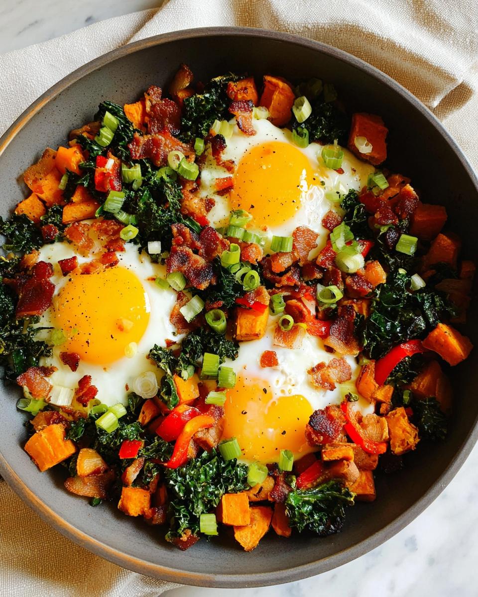 A delicious one-pan BREAKFAST SWEET POTATO hash with sunny-side-up eggs, crispy bacon, kale, and red peppers.