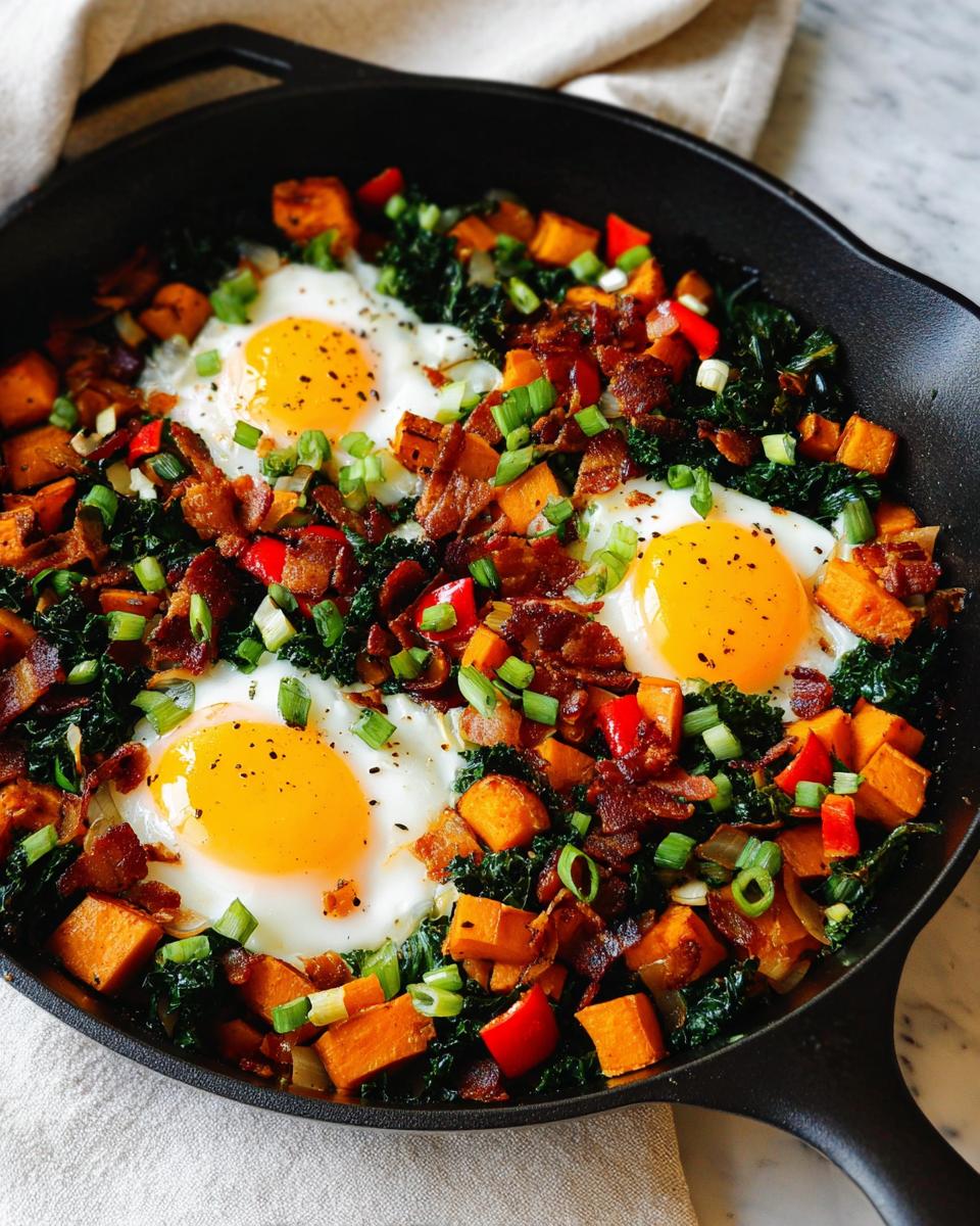 A close-up of a cast iron skillet filled with a savory BREAKFAST SWEET POTATO hash, featuring fried eggs, bacon, kale, and peppers.