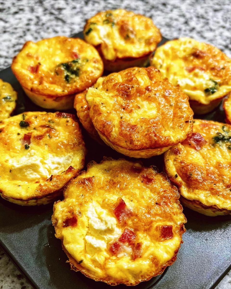 A close-up of golden-brown Cheesy Muffin Tin Cottage Cheese Egg Bites with visible cottage cheese and bits of red pepper.