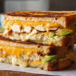 A stacked Chicken Avocado Melt Sandwich with melted cheese, chicken, and avocado slices.