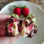 Close-up of a chocolate-covered strawberry yogurt cluster cut in half, revealing fresh strawberries and creamy yogurt.
