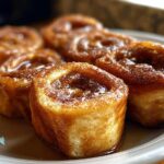 Close-up of delicious Cinnamon Roll French Toast Roll-Ups, glistening with syrup and dusted with cinnamon.