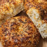 Close-up of homemade Cottage Cheese Flagels, one sliced in half, showcasing a fluffy interior and topped with everything bagel seasoning.