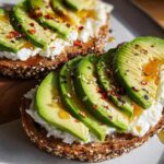 Close-up of EASY Avocado Toast with Cottage Cheese and Honey, topped with chili flakes and sesame seeds.