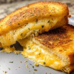 Close-up of a delicious Garlic Bread Grilled Cheese sandwich, oozing with melted cheese and sprinkled with herbs.