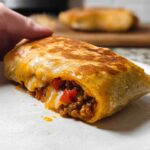 A close-up of a delicious Grilled Cheese Burrito Made Easy, showing the cheesy, meaty filling spilling out.