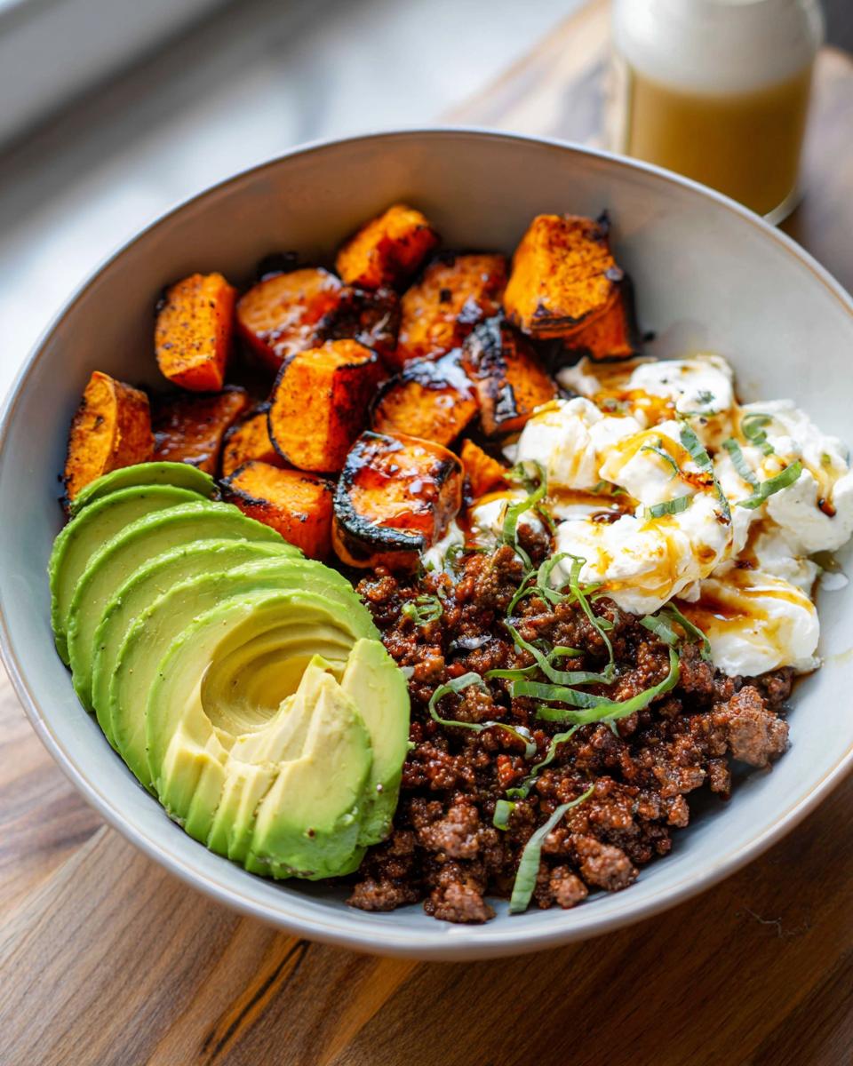 A delicious Ground Beef Hot Honey Bowl featuring seasoned ground beef, roasted sweet potatoes, sliced avocado, and creamy cheese.
