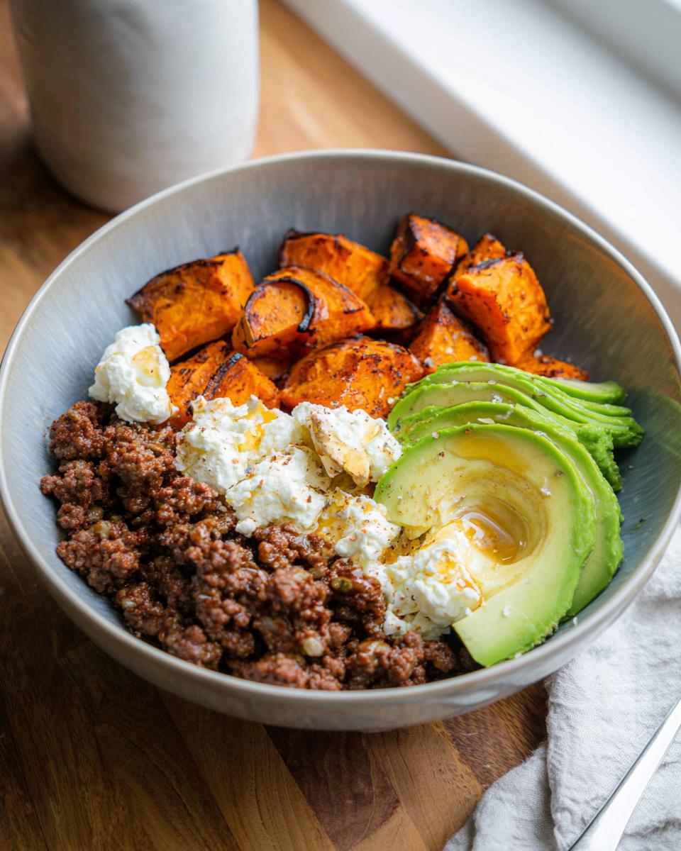 A delicious Ground Beef Hot Honey Bowl featuring seasoned ground beef, roasted sweet potatoes, creamy avocado, and dollops of cheese.