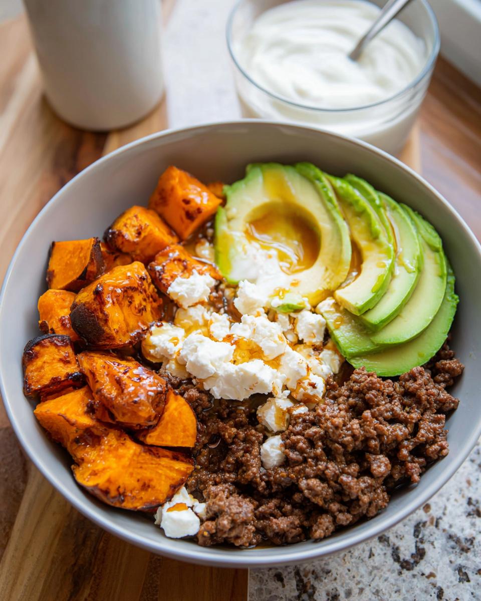 A delicious Ground Beef Hot Honey Bowl featuring seasoned ground beef, roasted sweet potatoes, sliced avocado, and crumbled feta cheese.