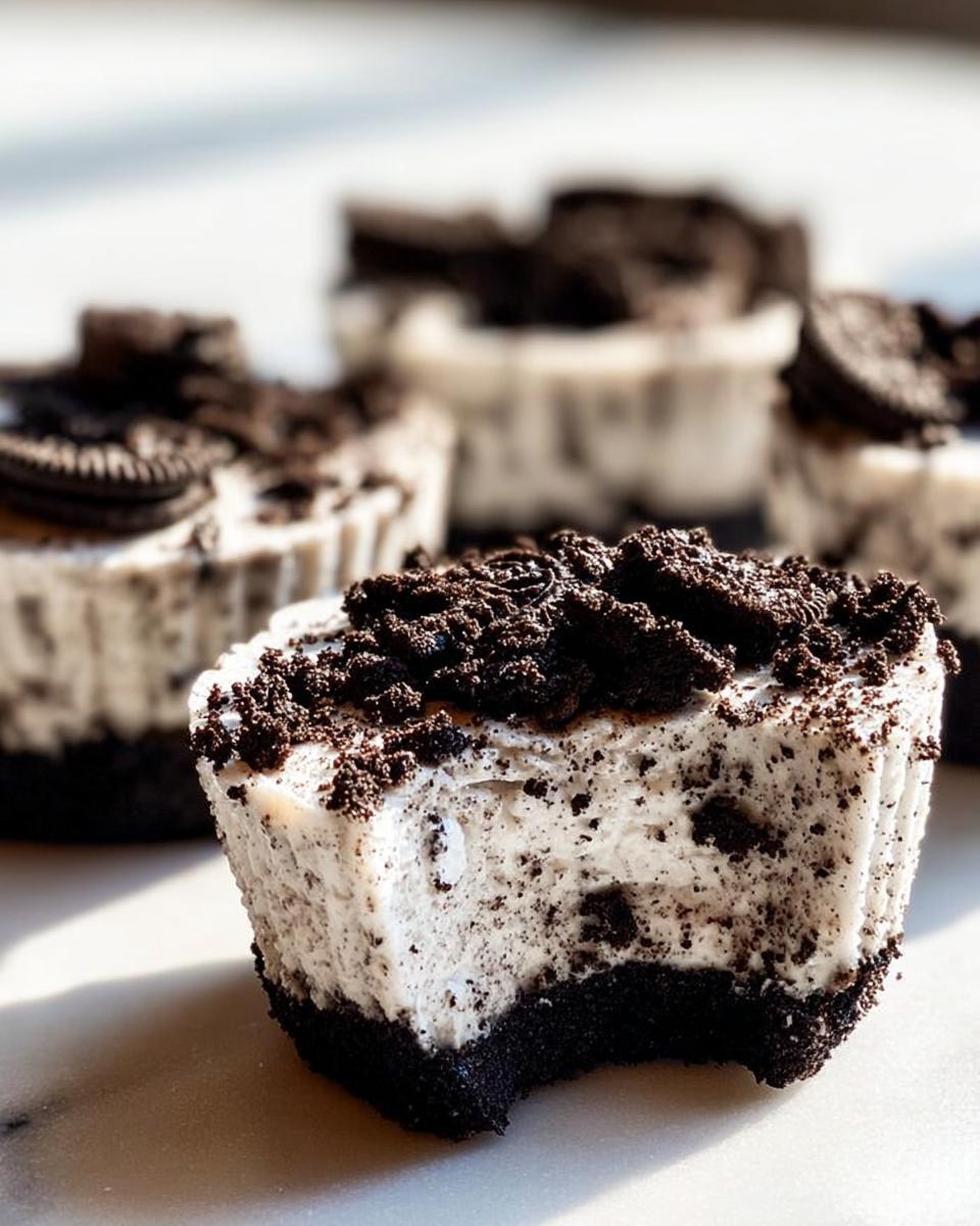 A close-up of a Healthy No-Bake Oreo Cheesecake Bite with a bite taken out, showing the creamy filling and Oreo cookie crust.