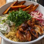 A delicious Hot Honey Chicken Bowl featuring grilled chicken, quinoa, sweet potato wedges, creamy slaw, and pickled red onions.