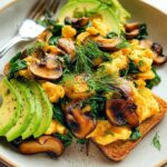 Delicious Mushroom Spinach Scrambled Eggs served on toast with avocado slices and fresh dill.