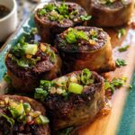 Close-up of delicious Thai Basil Beef Rolls, topped with fresh herbs and spices, served on a platter.