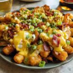 A plate of Ultimate Breakfast Poutine topped with creamy hollandaise sauce, bacon, and green onions.