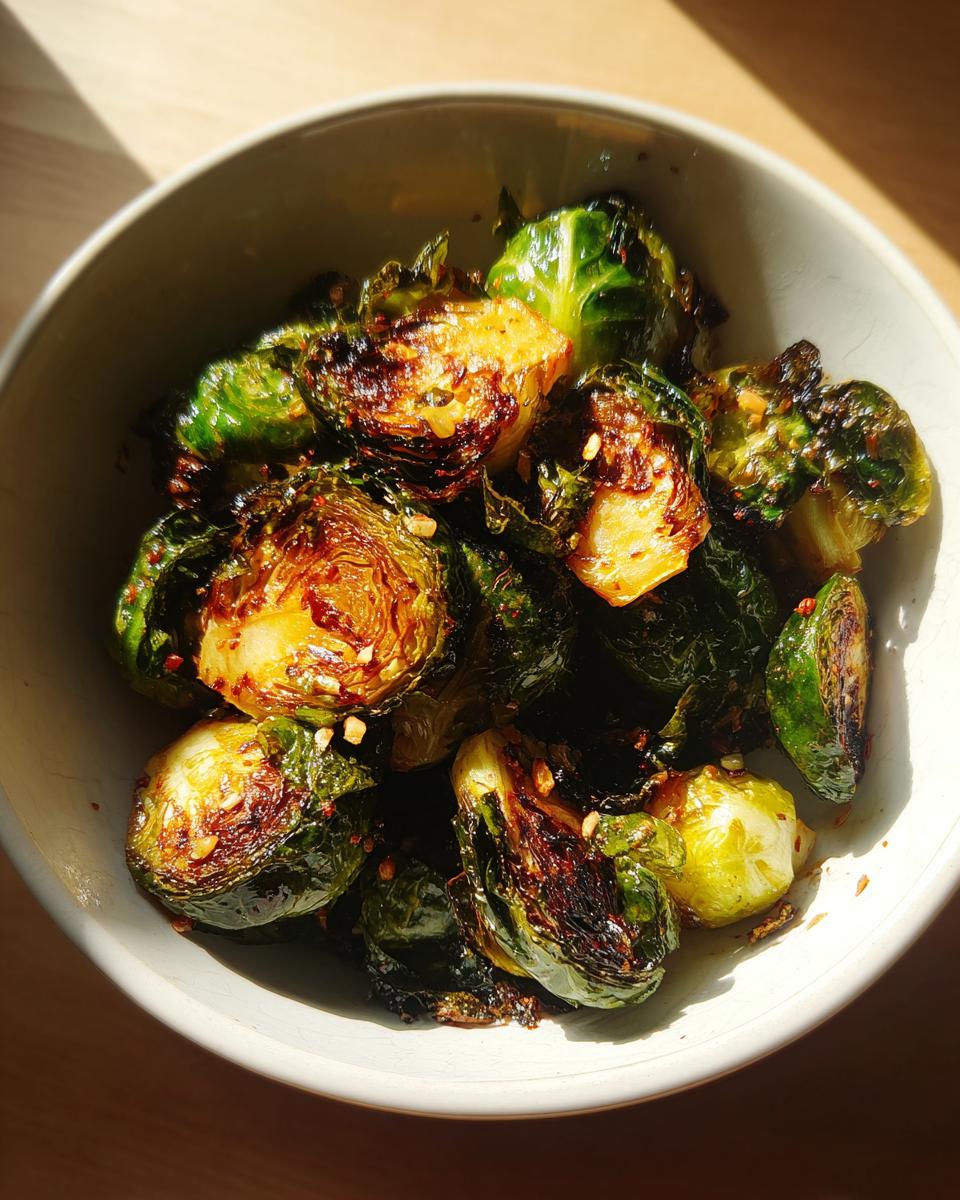 Close-up of perfectly crisp and caramelized air fryer brussels sprouts in a bowl, seasoned with spices.
