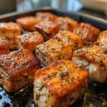 Close-up of perfectly cooked air fryer salmon bites seasoned with herbs, ready for a fast protein dinner.