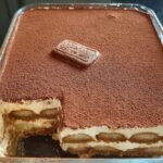 A delicious Biscoff Tiramisu in a glass dish, topped with cocoa powder and a Biscoff cookie.