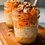 Close-up of Carrot Cake Overnight Oats in a glass jar, topped with shredded carrots and nuts.