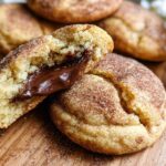 A close-up of a chewy churro cookie broken in half, revealing a rich, melted chocolate filling.