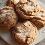 A close-up overhead view of five Chewy Churro Cookies dusted with sugar on a white plate.