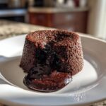 A rich chocolate lava cake with molten chocolate oozing out onto a white plate. Perfect for dessert recipes.