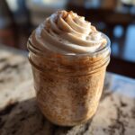 A jar of cinnamon roll overnight oats topped with whipped cream and cinnamon, perfect for breakfast ideas.