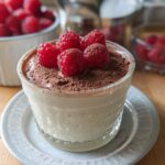 A delicate Cottage Cheese Raspberry Mousse served in a glass, topped with fresh raspberries and cocoa powder.