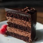 A decadent slice of Dark Chocolate Mousse Cake with layers of rich chocolate cake and creamy mousse, topped with chocolate shavings.