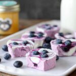 Close-up of Easy Blueberry Swirl Yogurt Bites topped with fresh blueberries on a white tray.
