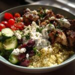 A vibrant Greek chicken bowl with grilled chicken, quinoa, cucumbers, tomatoes, olives, and feta cheese, perfect for healthy lunch ideas.