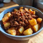 A blue bowl filled with ground beef sloppy joe mixture and crispy potato cubes, a delicious ground beef recipe.