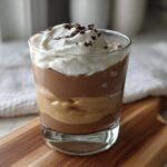 A layered High-Protein Cottage Cheese Peanut Butter Mousse in a glass, topped with whipped cream and chocolate shavings.