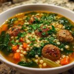 A close-up of a bowl of Italian Wedding Soup with meatballs, pasta, spinach, and carrots, perfect for chilly nights.