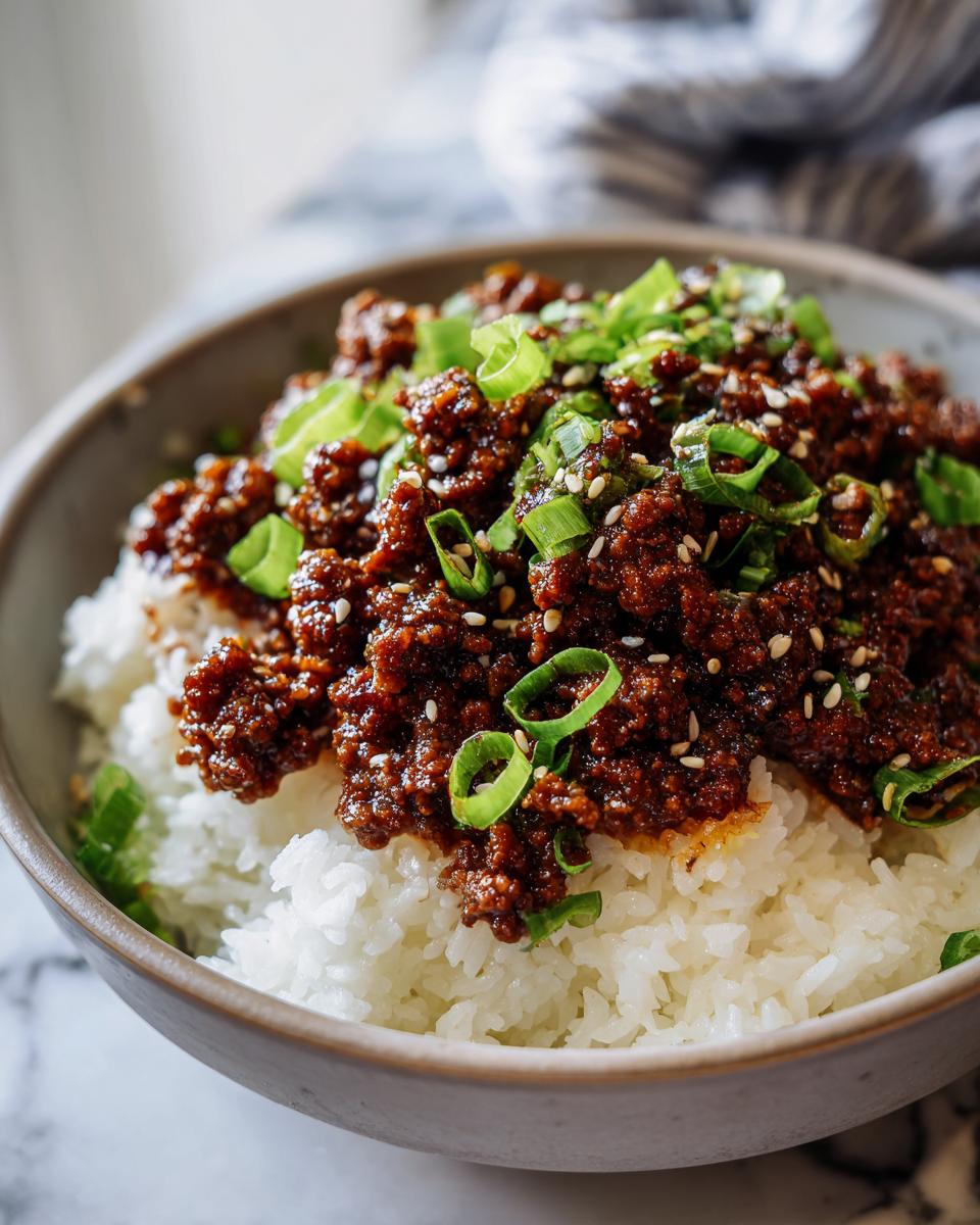 Close-up of a Korean beef rice bowl topped with ground beef, green onions, and sesame seeds.