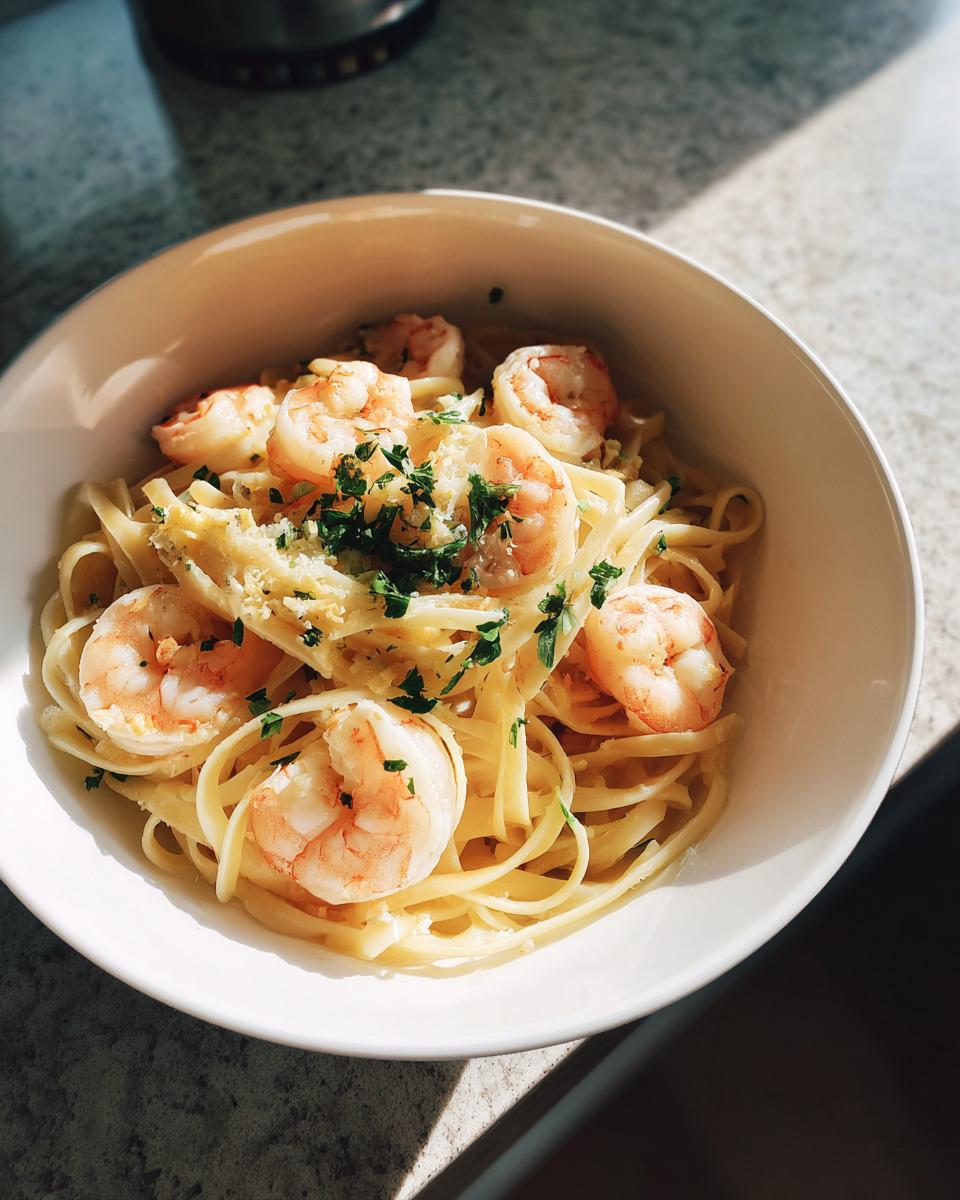 A bowl of delicious lemon shrimp linguine pasta, topped with fresh parsley and grated cheese.