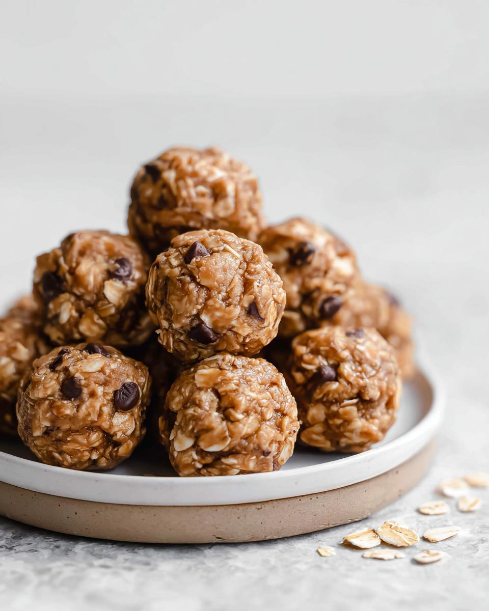 A pile of delicious No-Bake Chocolate Peanut Butter Protein Balls on a white plate with scattered oats.