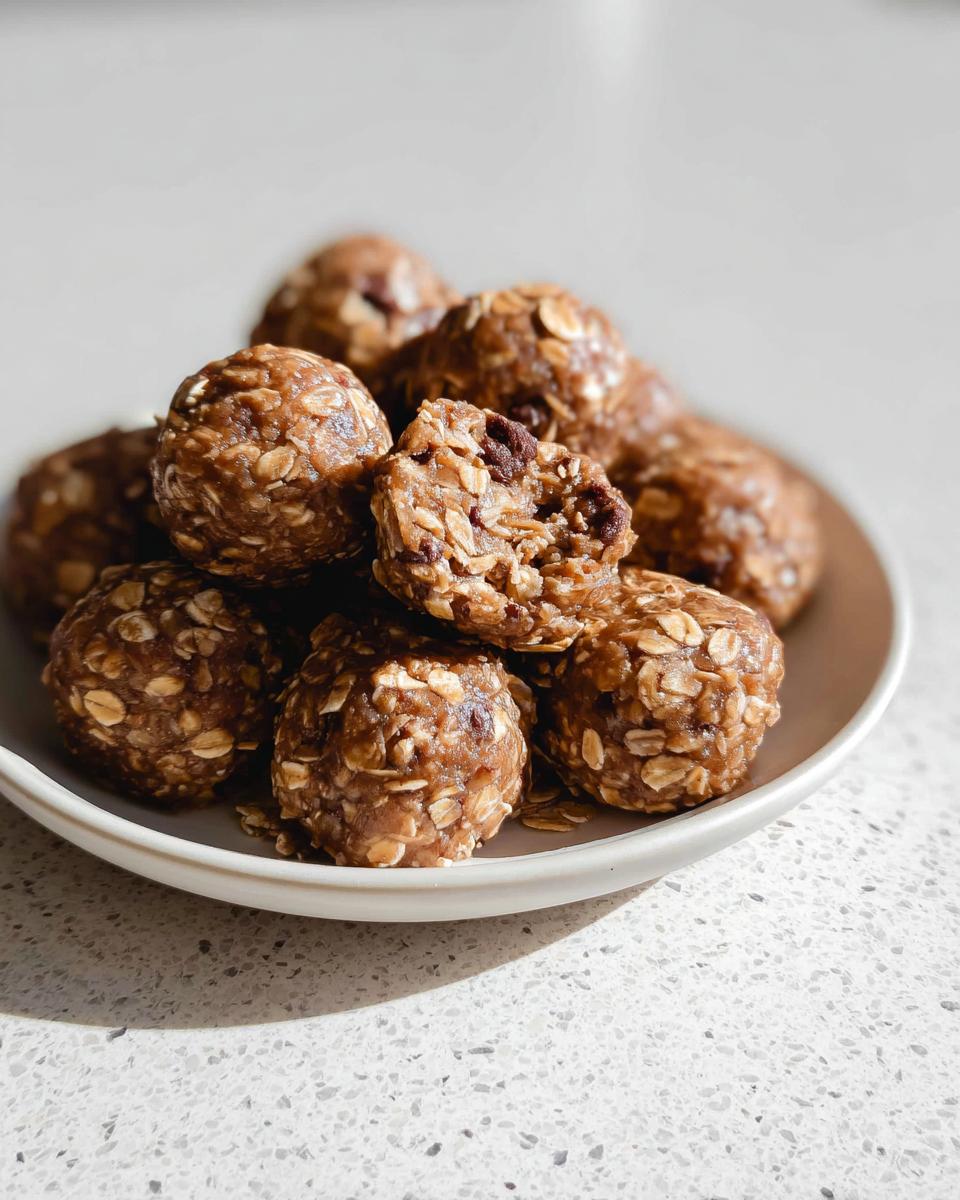 A close-up of a pile of No-Bake Chocolate Peanut Butter Protein Balls on a white plate.