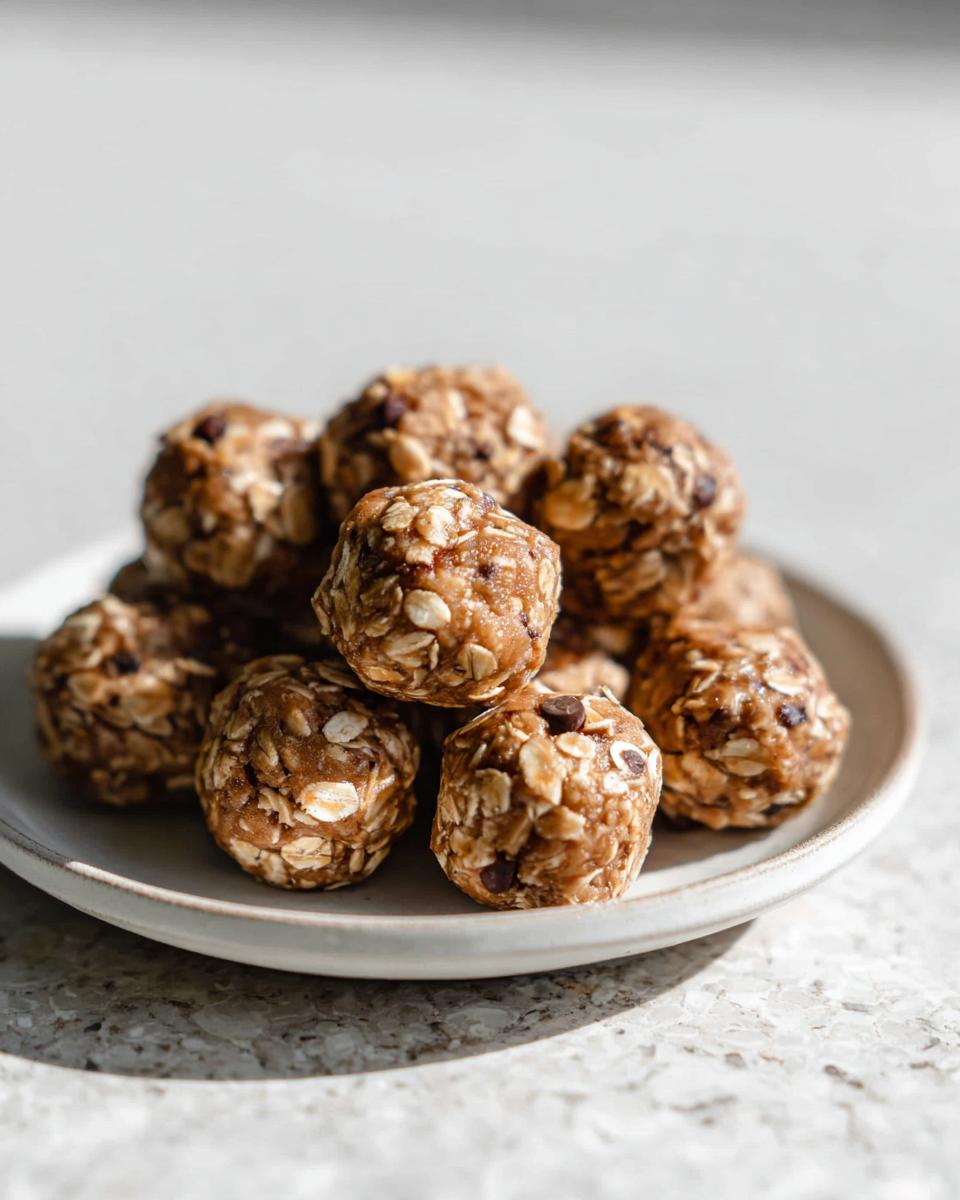 A close-up of a stack of No-Bake Chocolate Peanut Butter Protein Balls on a plate, showing oats and chocolate chips.