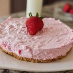 A whole no-bake strawberry cloud cake topped with a fresh strawberry.