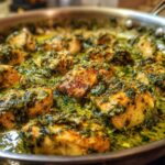 Close-up of pan-seared chicken breast pieces in a creamy pesto sauce in a stainless steel skillet.
