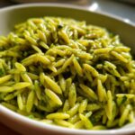 Close-up of a bowl of bright green pesto orzo pasta, showcasing the flavorful pasta.