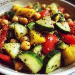 A vibrant bowl of Quinoa Chickpea Salad with chopped cucumber, tomatoes, bell peppers, and chickpeas.