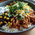 A delicious Slow Cooker Salsa Verde Chicken Taco Bowl filled with rice, shredded chicken, black beans, corn, cheese, and sour cream.