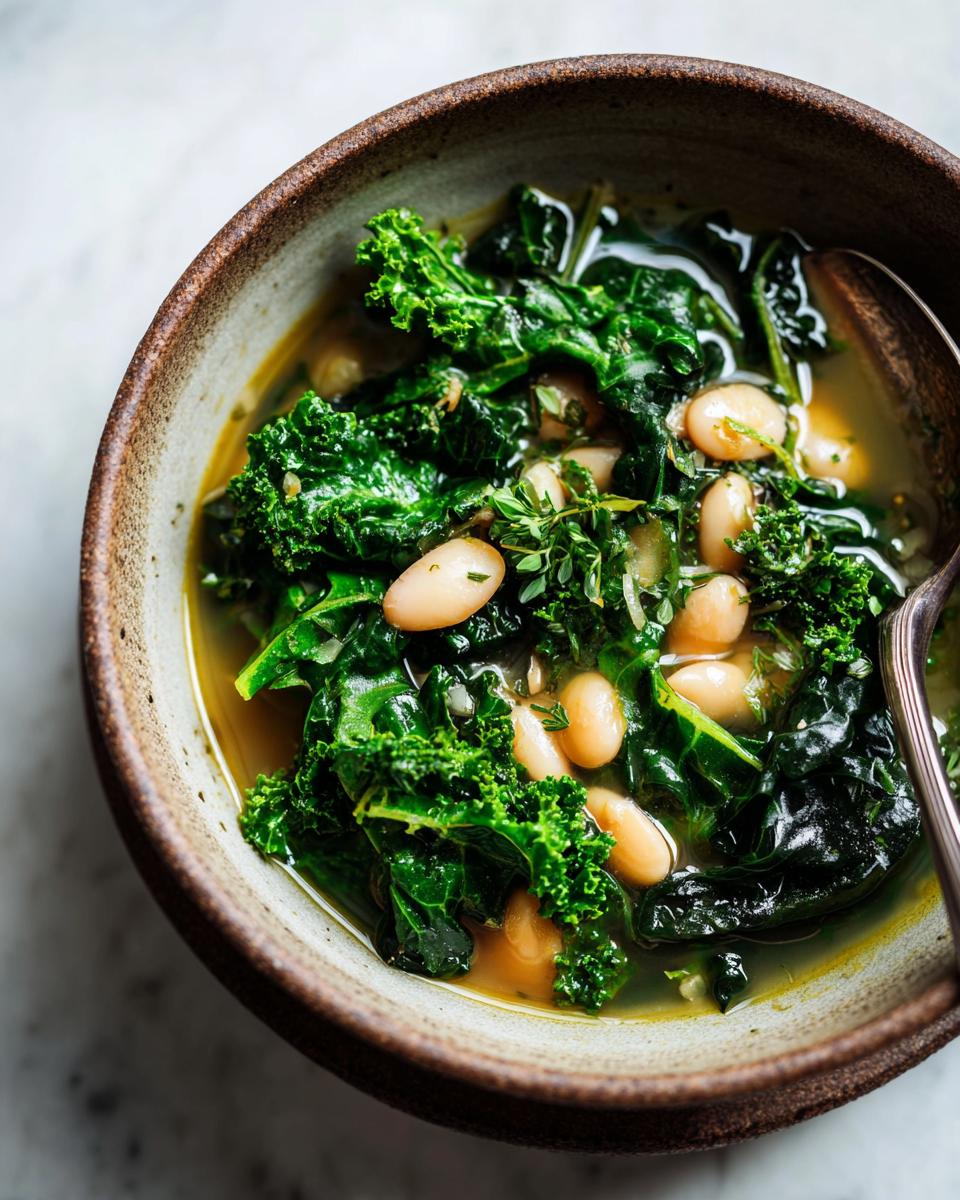 A close-up of a rustic bowl filled with hearty white bean kale soup, featuring tender kale leaves and creamy white beans.