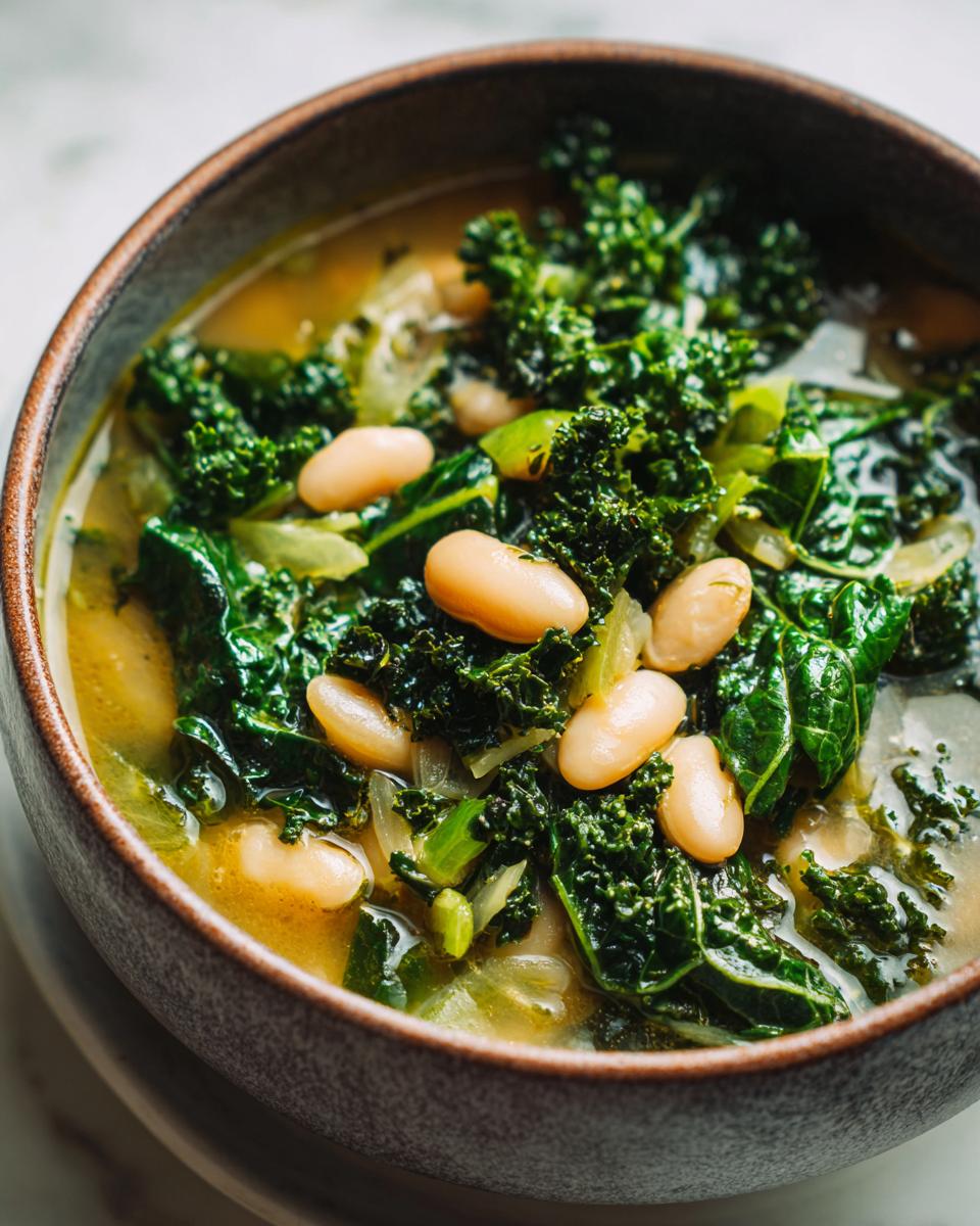 Close-up of a bowl of hearty white bean kale soup, showcasing tender kale leaves and creamy white beans in a savory broth.